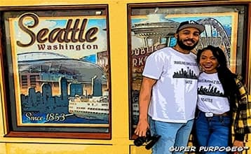 Couple smiling in front of poster wall of Seattle Washington. Empower Your Career. A woman of versatility.