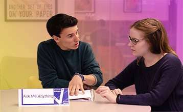 A young adult male sitting at a table with a young adult female providing career mentoring.
